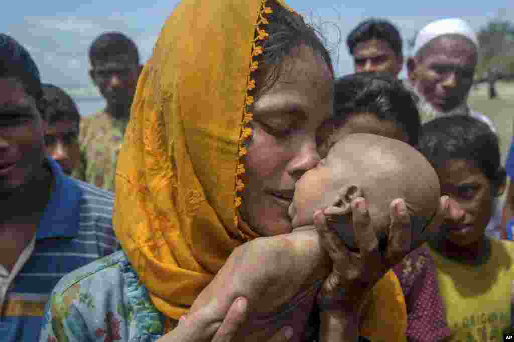 一位罗兴亚母亲亲吻她死去的婴儿。她乘坐的船从缅甸进入孟加拉湾在没有抵达孟加拉国海岸时翻覆，她的儿子死亡。（2017年9月14日）
