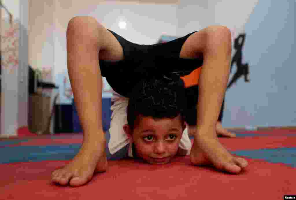 A Palestinian boy performs during a yoga and flexibility class on International Yoga Day in a club in Gaza City.