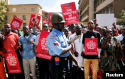 FILE - A riot policeman stands guard as doctors chant slogans after their case to demand fulfilment of a 2013 agreement between their union and the government that would raise their pay and improve working conditions in Kenya, Feb. 13, 2017.