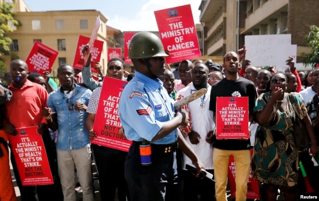 FILE - A riot policeman stands guard as doctors chant slogans after their case to demand fulfilment of a 2013 agreement between their union and the government that would raise their pay and improve working conditions in Kenya, Feb. 13, 2017.