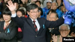 Nago City Mayor Susumu Inamine (C), flanked by his wife Ritsuko, celebrates after he was re-elected in the mayoral election in Nago, on the Japanese southern island of Okinawa, Jan. 19, 2014. 