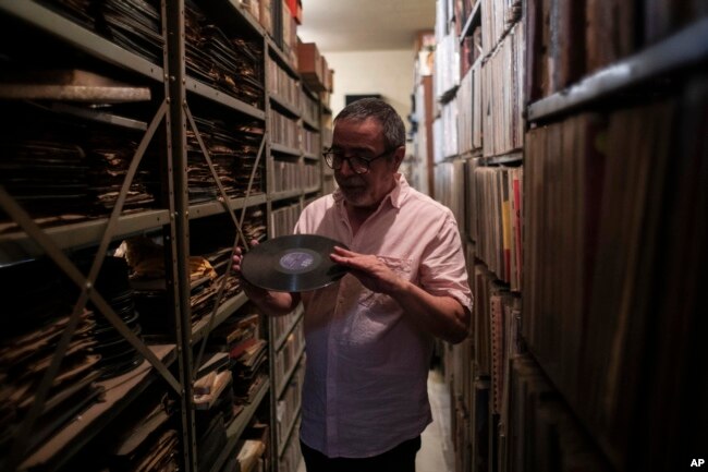 Carlos Savalla holds an album produced by the Brazilian record company RGE founded in 1947, in his studio where he maintains his music collection. Savalla, a 66-year-old music producer in Rio, owns more than 60,000 vinyl records. (AP Photo/Bruna Prado)