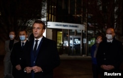French President Emmanuel Macron, flanked by offcials, speaks to the press following a stabbing attack at a school in the Conflans-Sainte-Honorine suburb of Paris, France, Oct. 16, 2020.