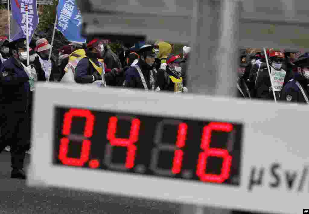 Demonstrators march during an anti-nuclear protest, as a monitor displaying the current radiation level shows a reading of 0.416 microsievert/hour, in Koriyama, Fukushima prefecture, March 11, 2012. (Reuters)