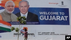 An Indian man walks past a hoarding put up to welcome Israeli Prime Minister Benjamin Netanyahu that features him along with Indian Prime Minister Narendra Modi at the International Centre for Entrepreneurship and Technology (iCreate) near Bavla in Ahmada