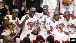 Tim Miami Heat berpose bersama, sesaat setelah berhasil memenangkan Kejuaraan Liga NBA (22/6). Dwyane Wade (kiri) memegang Piala NBA "Larry O'Brien" dan LeBron James (dua dari kiri) memegang pialanya sebagai pemain terbaik NBA tahun ini.