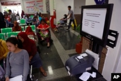 Patients wait near a queue number dispenser affected by "WannaCry" attack at Dharmais Cancer Hospital in Jakarta, Indonesia, May 15, 2017.