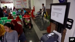 Pasien berdiri dekat mesin antrian yang terinfeksi serangan malware “WannaCry” di RS Kanker Dharmais di Jakarta, Indonesia, 15 Mei 2017 (foto: AP Photo/Dita Alangkara)