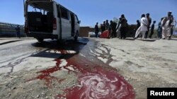 Afghan residents watch as a man washes a damaged minivan after was hit by a remote-controlled bomb in Kabul, July 15, 2014. 