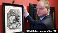 Uffizi Gallery director Eike Schmidt holds up a copy of "Vase of Flowers" by Dutch artist Jan van Huysum, with writing in red reading "Stolen."