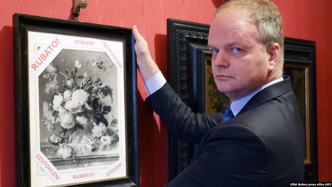 Uffizi Gallery director Eike Schmidt holds up a copy of "Vase of Flowers" by Dutch artist Jan van Huysum, with writing in red reading "Stolen."
