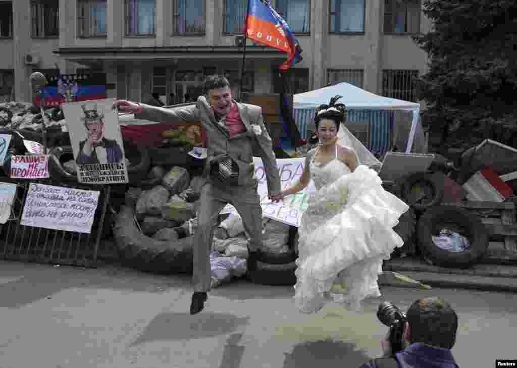 A bride and groom jump for a picture in front of barricades outside a regional government building seized by pro-Russian armed men in Kramatorsk, eastern Ukraine.