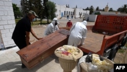 Des employés de la municipalité tunisienne chargent le corps d'une victime du COVID-19 dans un camion à l'hôpital Ibn al-Jazzar de la ville de Kairouan, dans le centre-est, le 4 juillet 2021.