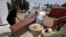 Des employés de la municipalité tunisienne chargent le corps d'une victime du COVID-19 dans un camion à l'hôpital Ibn al-Jazzar de la ville de Kairouan, dans le centre-est, le 4 juillet 2021.