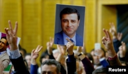 A supporter holds a portrait of Selahattin Demirtas, detained leader of Turkey's pro-Kurdish opposition Peoples' Democratic Party at a meeting at the Turkish parliament in Ankara, Nov. 8, 2016.