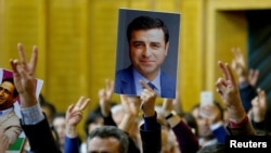 FILE - A supporter holds a portrait of Selahattin Demirtas, detained leader of Turkey's pro-Kurdish opposition Peoples' Democratic Party, at a meeting at the Turkish parliament in Ankara, Nov. 8, 2016.