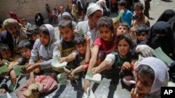 FILE - Yemenis present documents in order to receive food rations provided by a local charity, in Sana'a, Yemen, April, 13, 2017. 