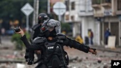 Un oficial de policía se prepara para lanzar una granada aturdidora a los manifestantes durante un paro nacional contra la reforma tributaria en Cali, Colombia, el lunes 3 de mayo de 2021.