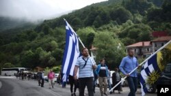 Penentang perjanjian antara Yunani dan Makedonia mengenai perubahan nama Makedonia menjadi Republik Makedonia Utara membawa bendera Yunani ketika protes di desa Pisoderi dekat perbatasan dengan Makedonia di Yunani utara, 17 Juni 2018. 