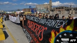 Ratusan pengunjuk rasa berbaris di markas penjaga pantai Yunani dan badan perbatasan Uni Eropa(Frontex), sambil memegang spanduk bertuliskan "pembunuh" di pelabuhan Piraeus, Minggu (18/6).