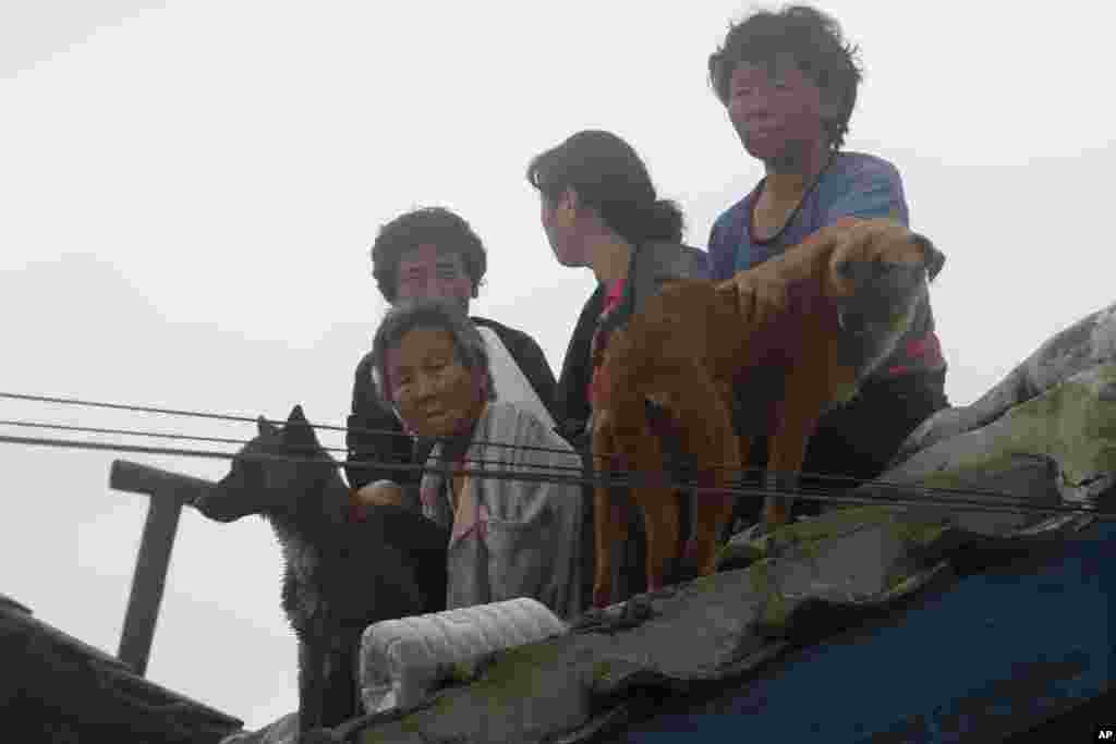 평안남도 안주시에서 홍수로 불어난 물을 피해 지붕 위로 대피한 주민들.