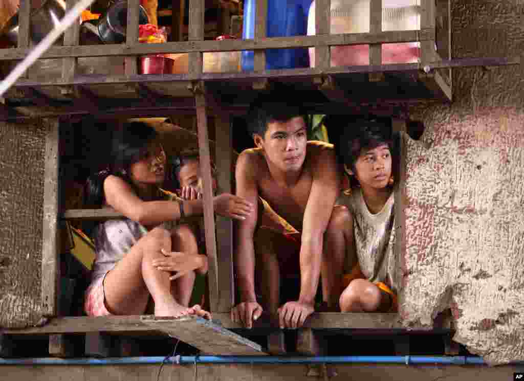 Residents watch volunteers clean an area that was hardly hit by floods in suburban Quezon city, north of Manila, Philippines, August 12, 2012.