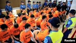 Policemen guard some of the 43 arrested foreigners, mostly Chinese nationals, for kidnapping a Singaporean woman at a casino resort in the capital, during a presentation inside the Philippine National Police (PNP) Headquarters in Quezon City, metro Manila, Philippines, July 20, 2017.