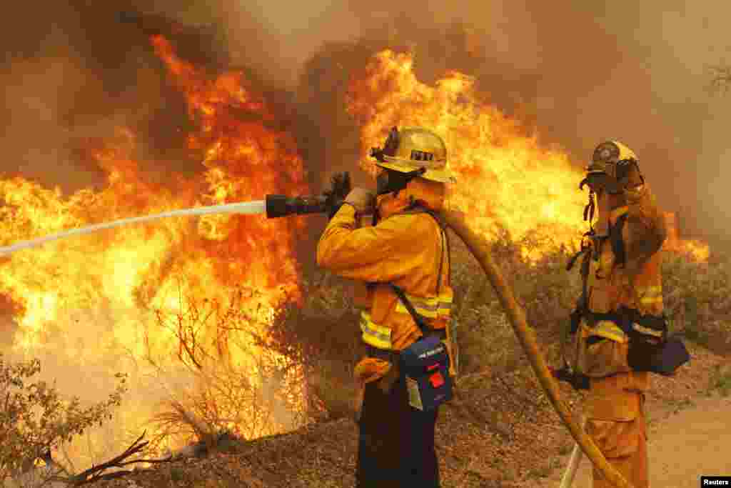 Firefighters battle the Springs Fire at Point Mugu State Park in California. A wind-driven wildfire raged along the California coast north of Los Angeles, threatening some 3,000 homes and prompting evacuations of a university campus and several residential areas.