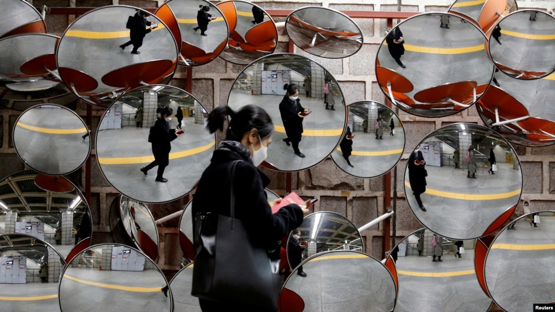 A woman wearing a mask to prevent the coronavirus is reflected in the mirrors, in Seoul, South Korea, February 24, 2020. REUTERS/Heo Ran/File Photo
