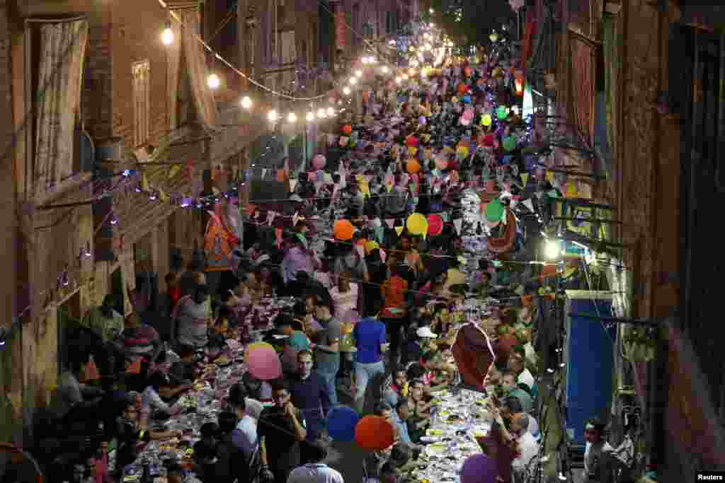 Residents of Ezbet Hamada in Cairo's Mataria district, Egypt, gather to eat Iftar, the meal to end their fast at sunset, during the holy fasting month of Ramadan, May 20, 2019.