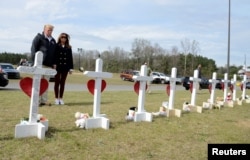 U.S. President Donald Trump and first lady Melania Trump pause at a row of crosses for the victims of a tornado in Beauregard, Alabama, March 8, 2019.