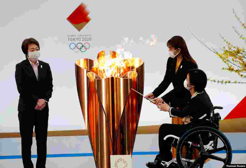 후쿠시마현 나라하에서 열린 도쿄올림픽&#183;패럴림픽 성화 봉송 출발 행사에서 하시모토 세이코 올림픽조직위원장이 지켜보는 가운데 배우 이시하라 사토미와 패럴림픽 국가대표 아키 타구치가 성화봉에 불을 붙이고 있다. 