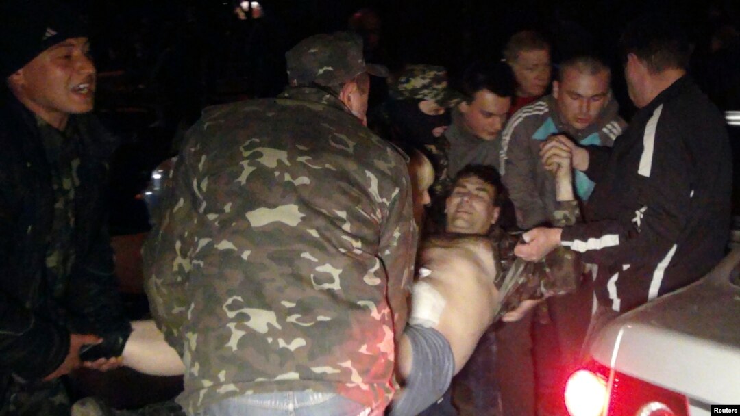 Warga membawa pria yang terluka dalam protes pro-Rusia dekat markas militer Ukraina di Mariupol (16/4). 