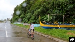 Boys pedal their way past boats placed on a safer area in Legazpi city, central Philippines as Typhoon Melor slammed into the eastern Philippines, Monday, Dec. 14, 2015.