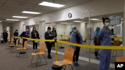 Health care workers wait in line to receive the Pfizer-BioNTech COVID-19 vaccine at Seton Medical Center in Daly City, Calif., Dec. 24, 2020. 