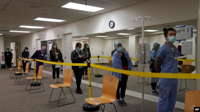 Healthcare workers wait in line to receive the Pfizer-BioNTech COVID-19 vaccine at Seton Medical Center in Daly City, Calif., Thursday, Dec. 24, 2020. (AP Photo/Jeff Chiu)