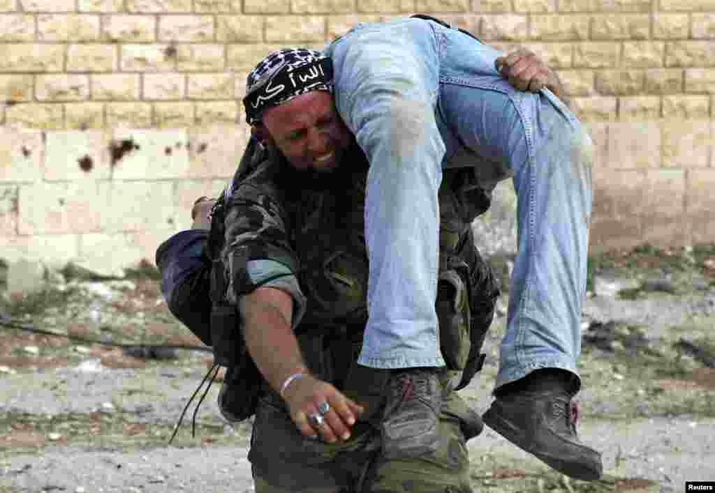 A Free Syrian Army fighter reacts as he carries the body of a fellow fighter after he was killed by a sniper loyal to Syria's President Bashar al-Assad in Khan al-Assal area November 10, 2012. Picture taken November 10, 2012. The headband on the fighter r