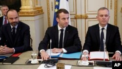 French President Emmanuel Macron, center, Prime Minister Edouard Philipppe, left, and Environment Minister Francois de Rugy meet with representatives of trade unions, employers' organizations and local elected officials at the Elysee Palace in Paris, Dec. 10, 2018.