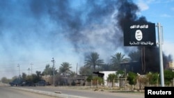 지난해 11월 이라크 바그다드 북부 사디야 지역에서 정부군과 이슬람 수니파 무장단체 ISIL의 무력충돌이 있은 후 ISIL 깃발 너머로 연기가 치솟고 있다. (자료사진)