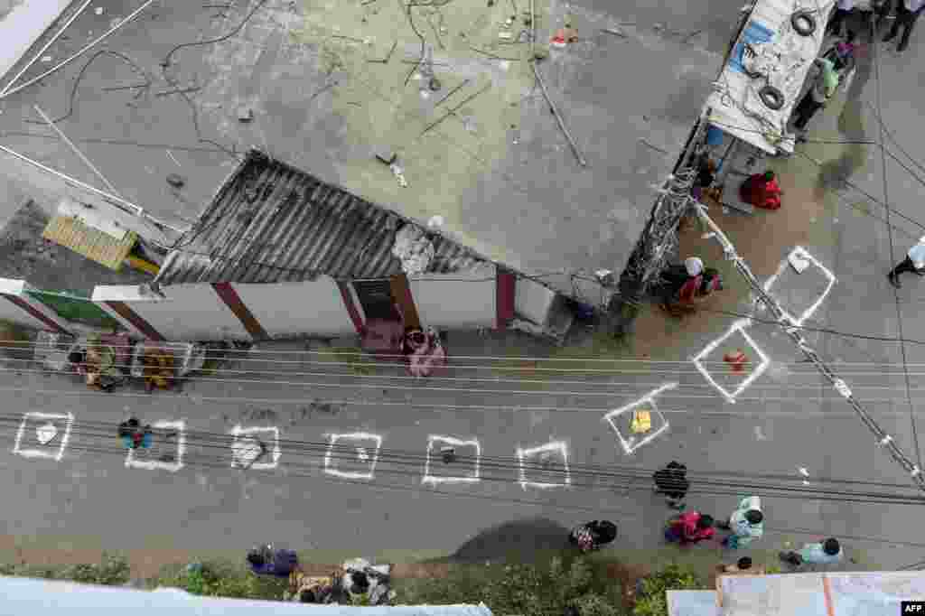 People wait inside marked areas on a street to receive free rice distributed at a government store during a nationwide lockdown to preventive the spread of the coronavirus, in Hyderabad, India.