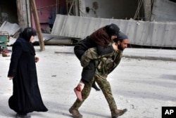 In this photo released by the Syrian official news agency SANA, a Syrian soldier carries a wounded woman in eastern Aleppo, Syria, Dec. 12, 2016.