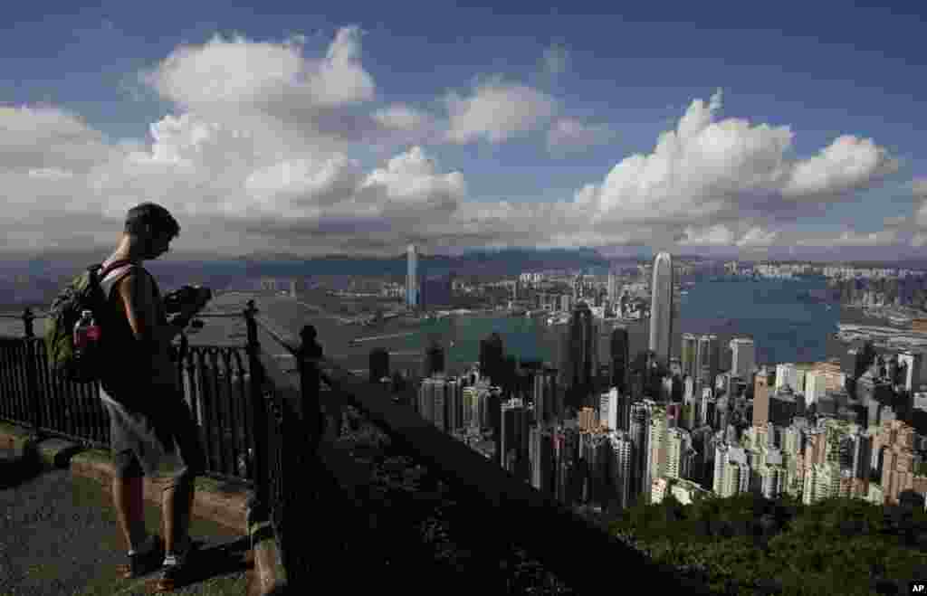 یک گردشگر بر فراز قلۀ ویکتوریا در شهر هانگ کانگ ایستاده و در حال عکسبرداری از منظرۀ شهر است.