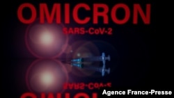 This photograph taken on Dec. 1, 2021 shows syringes and a screen displaying Omicron, the name of the new covid 19 variant in Toulouse, southwestern France. 