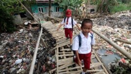 Students cross a bamboo bridge, above a garbage-filled stream branching off the Ciliwung River, in Bogor, Indonesia, September 25, 2018.