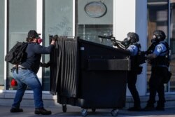 A protestor faces off with two police officers using less-lethal ammunition in their weapons, May 28, 2020, in St. Paul, Minn.