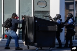 A protestor faces off with two police officers using less-lethal ammunition in their weapons, May 28, 2020, in St. Paul, Minn.