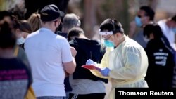 A medical staff member takes details from people queuing at a COVID-19 testing site in Adelaide, Nov. 17, 2020.