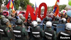 Police officers block a street as protesters march to the Cambodia National Assembly during a protest in Phnom Penh July 13, 2015. Cambodia passed on Monday a contentious law to regulate non-governmental organisations (NGOs) which government critics fear will be used to muzzle opposition. REUTERS/Samrang Pring