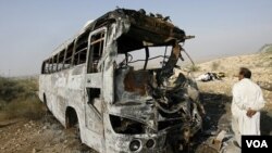 Seorang pria mengamati kerusakan bus yang terbakar akibat bertabrakan dengan mobil tangki minyak di Pakistan.