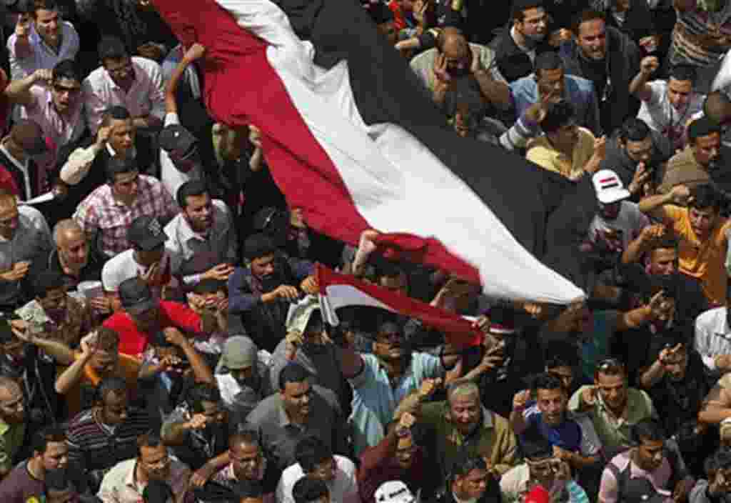 Egyptians shout as they wave a giant flag during a demonstration at Tahrir Square, Cairo, April 1, 2011, to call for the military government to harshly punish members of ex-President Hosni Mubarak's former administration